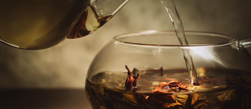 Heet water wordt rustig langs de wand van het glas geschonken bij thee-infusie